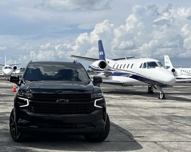 Black luxury SUV parked on the tarmac beside a private jet